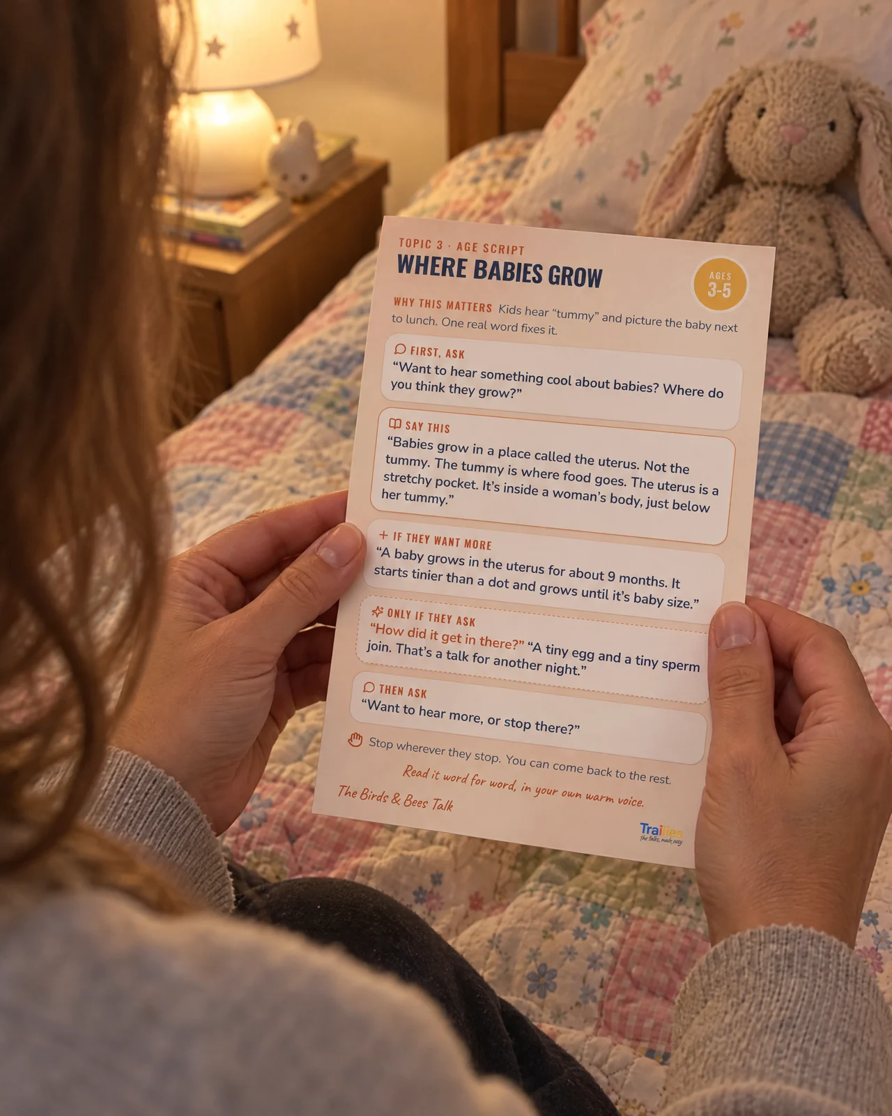 A parent sitting on a child's bed at night, holding a Birds & Bees card