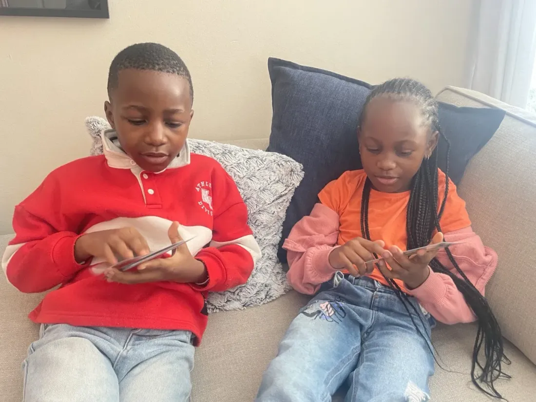 Two children sitting together, each looking through a deck of Trailies cards
