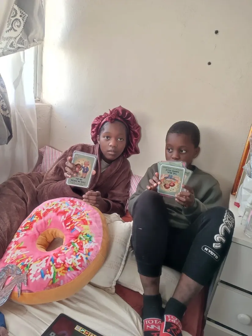 Two children holding up Trailies body-safety cards toward the camera