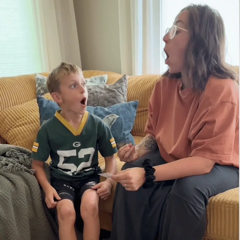 A parent and child reading from a Trailies card together at home