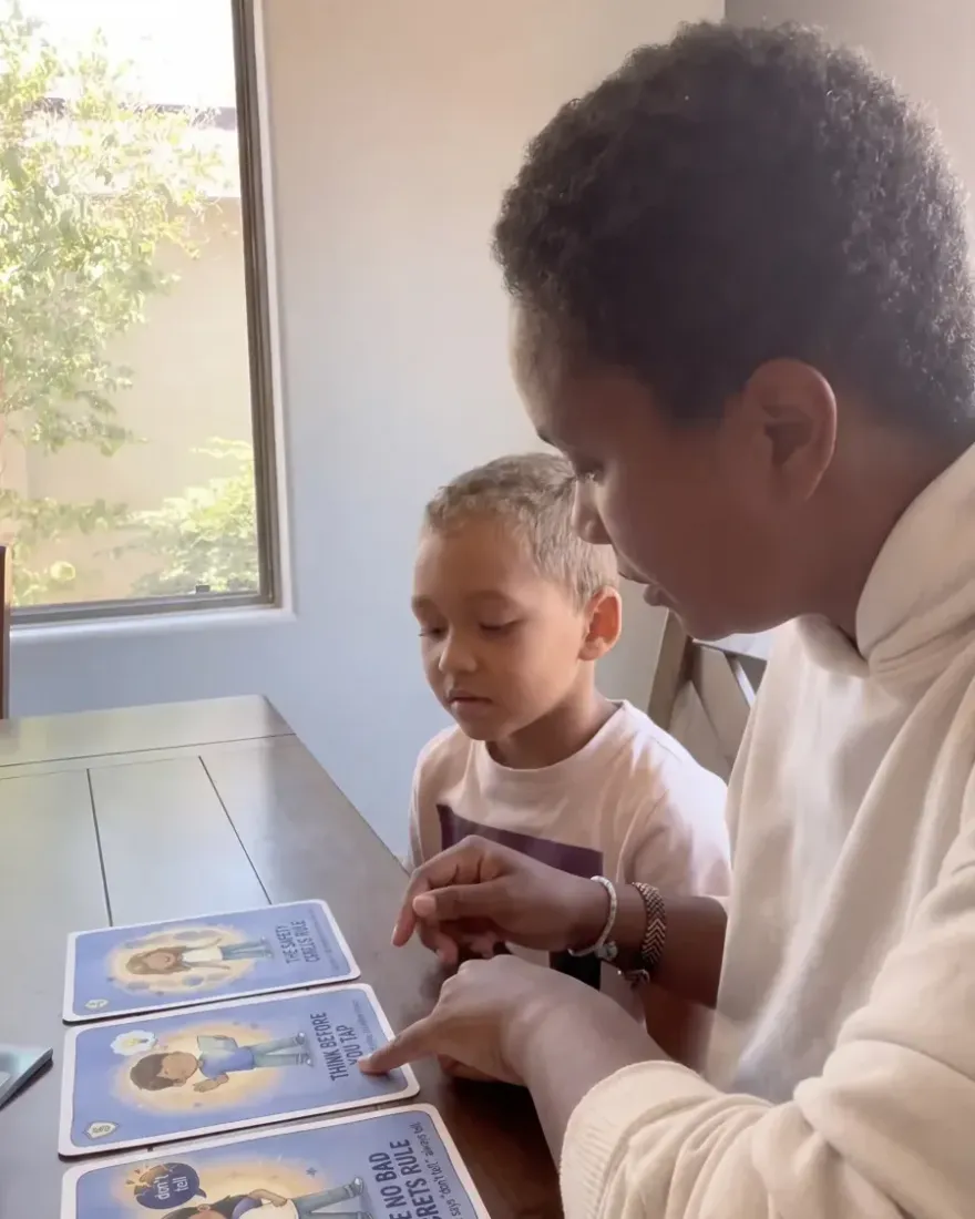 Parent helping child work through a Trailies card at the table during a hard moment