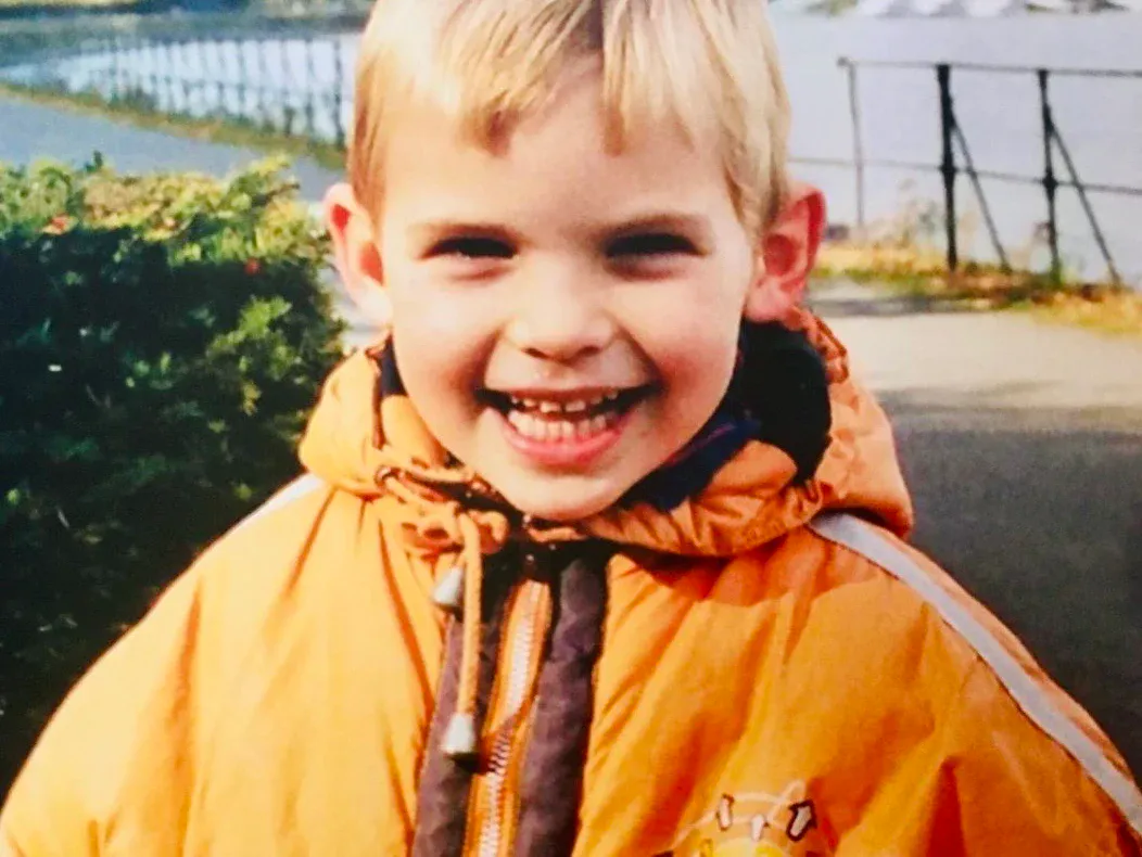 Jonah as a young kid, smiling in an orange jacket